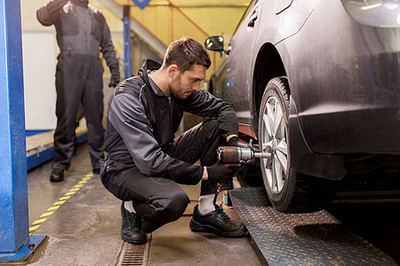 汽车服务,维修,维护人的汽车技工与螺丝刀更换轮胎车间雪上汽车机械师与螺丝刀更换汽车轮胎